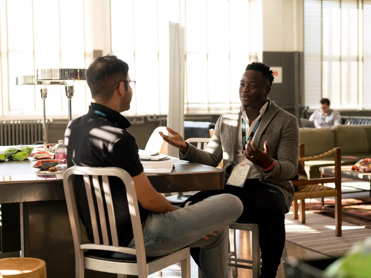 Two men in a candid mentoring conversation at a community table; licensed stock photograph, not foundation participants