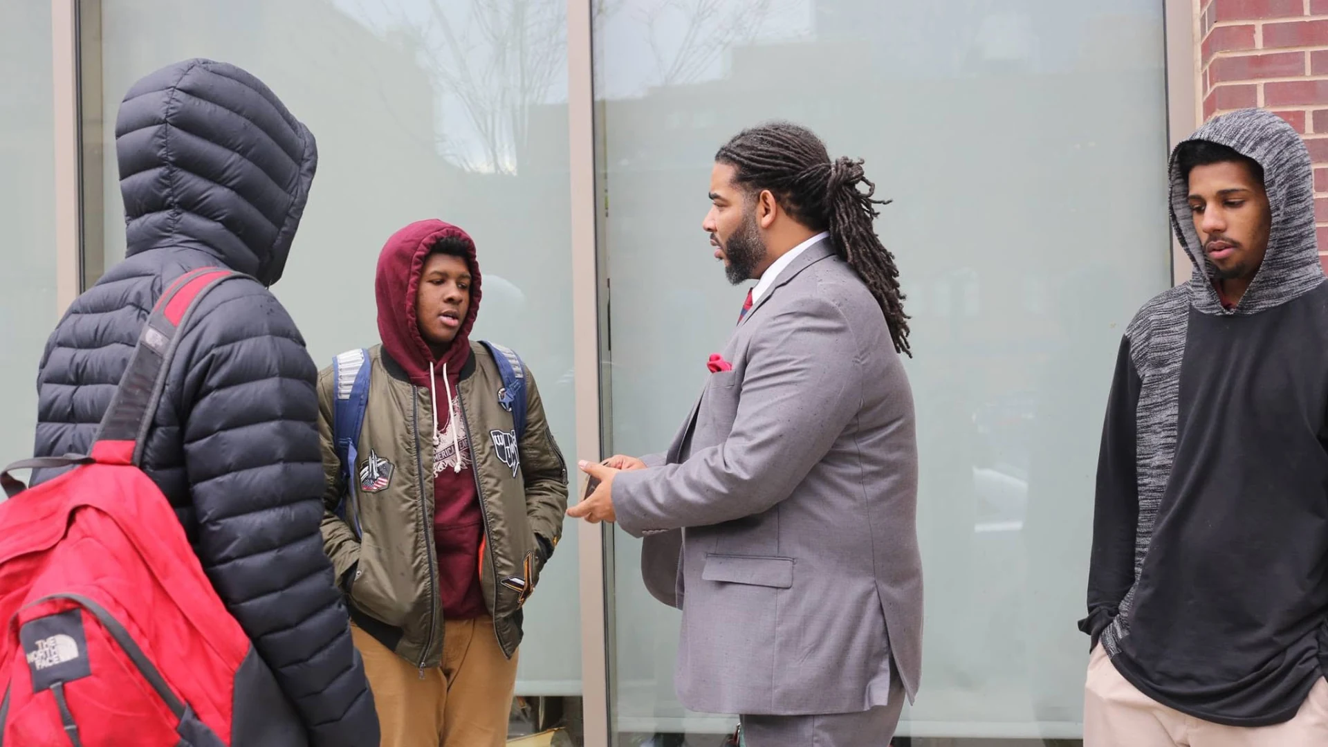 A man in a gray suit speaking with young men outside, in a photograph supplied by the Love family